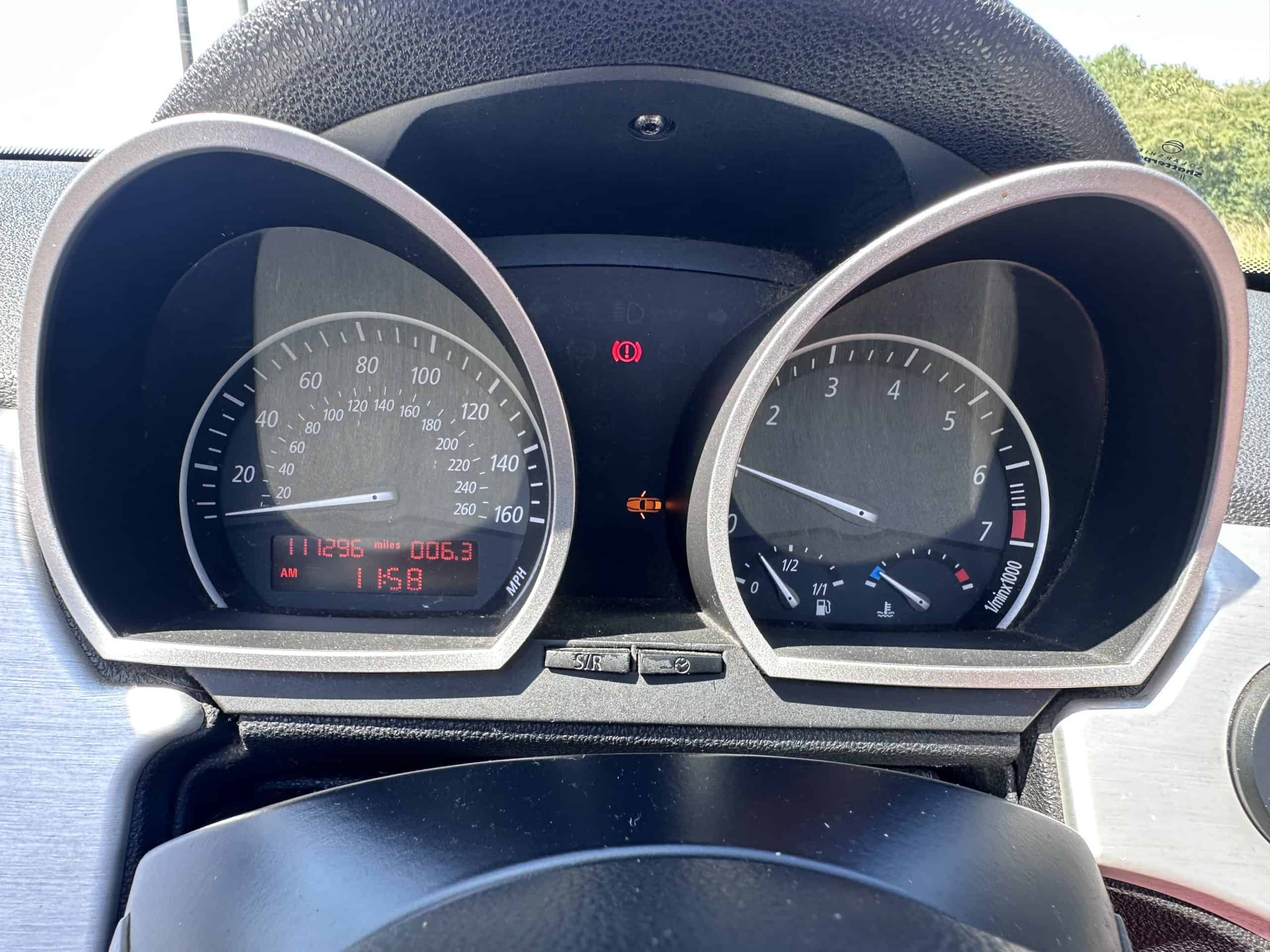 Close-up of car dashboard showing warning lights and speedometer.