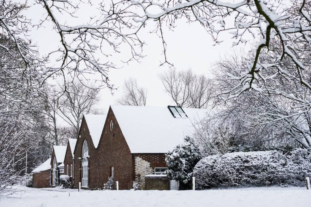 Snow-covered church with brick exterior and tall arched windows in winter landscape.