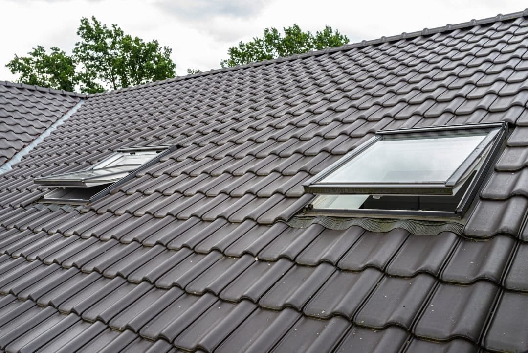 High-quality black ceramic tile roofing with skylights on a residential house, showcasing durable and stylish roofing solutions.