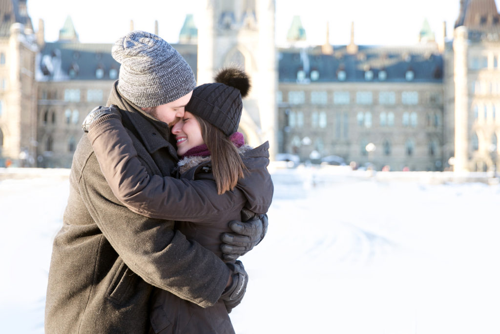 Couple laughing in front of the parliament buildings wearing black coats and tuques Couple in a white sweater and jean outfit hugging and laughing in front of an willow Tree in the Dominion Arboretum during an engagement session engaged couple walking through magnolia blossoming trees, dominion arboretum Ottawa, white magnolias, engagement photo with a dog spring cherry blossom Engagement Session Downtown Ottawa during Sunset  grey loft studio ottawa wedding photographer videographer engagement kanata orleans nepean beautiful locations for engagement photos in ottawa dominion arboretum magnolia blooms spring photos ottawa photo studio boxer puppy ottawa dogs in engagement photos ottawa