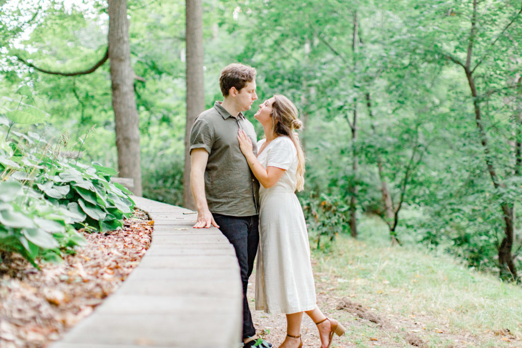 Cute Couple posing during an Engagement Session - Neutral colours - Long white Linen Dress paired with Tan open toed heels. Hair half up half down. Posing at the Ottawa Arboretum - Grey Loft Studio - Ottawa Wedding Photographer - Ottawa Wedding Videographer