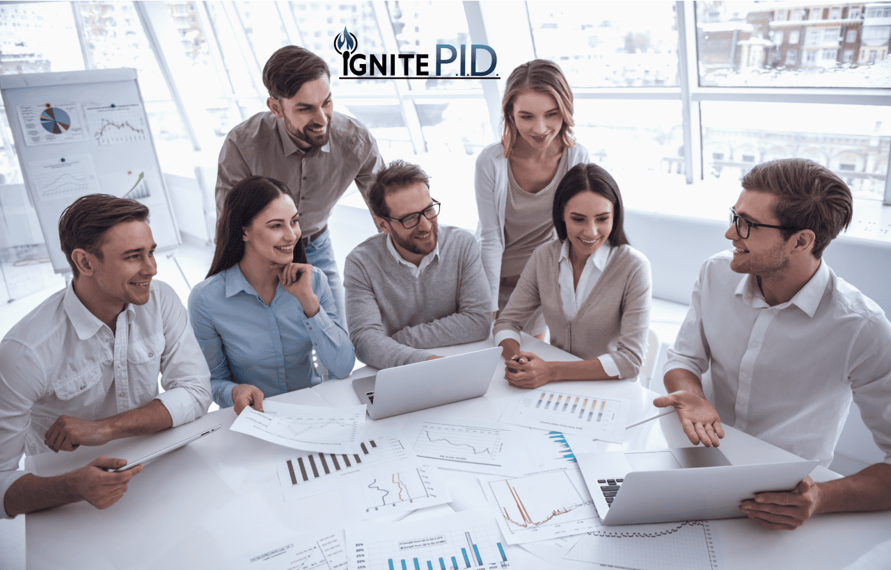 Team of professionals collaborating around laptops and financial charts during an Ignite PID strategy session