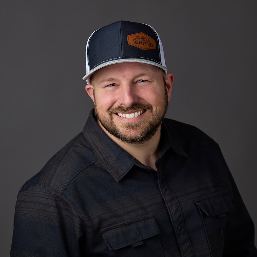 Andy, owner of Grow Ignited, smiling in a branded hat during a professional headshot