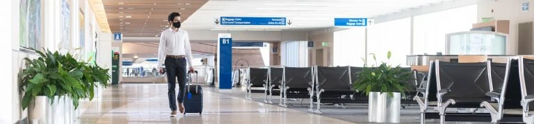 Man pulling a suitcase walking down concourse B at GSP airport.