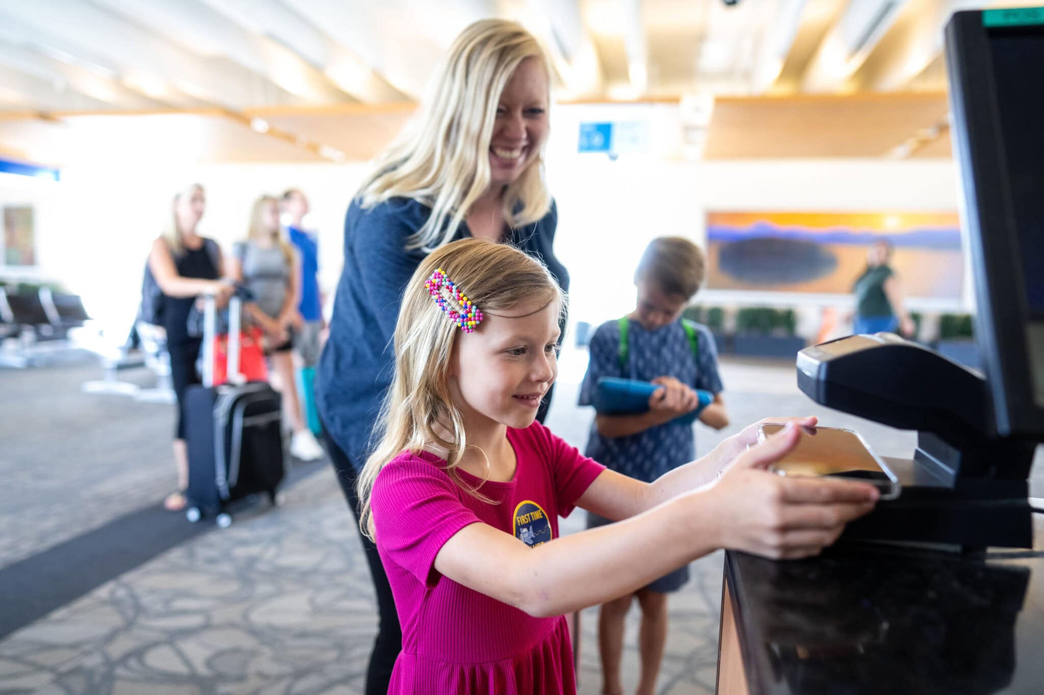 Girl scanning boarding pass at gate with woman smiling and helping