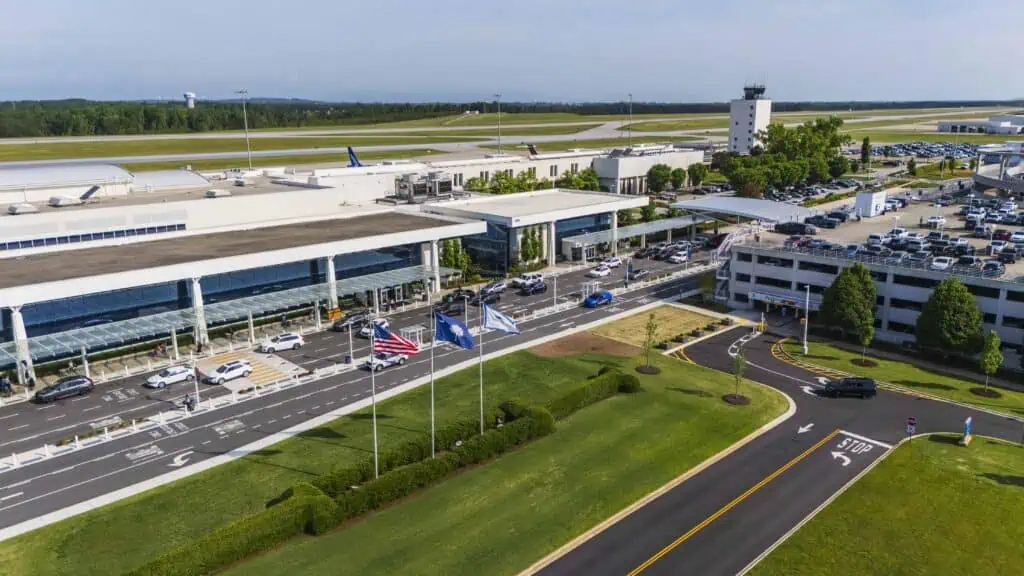 Aerial images of the front of the terminal with waving flags and air traffic control tower and runway in the background.