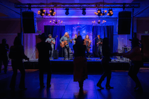 Wood Box Heroes perform while dancers on the floor in silhouette.