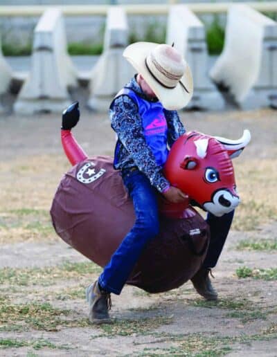 A young buckeroo rides a fierce beast of a bouncing bull toy.