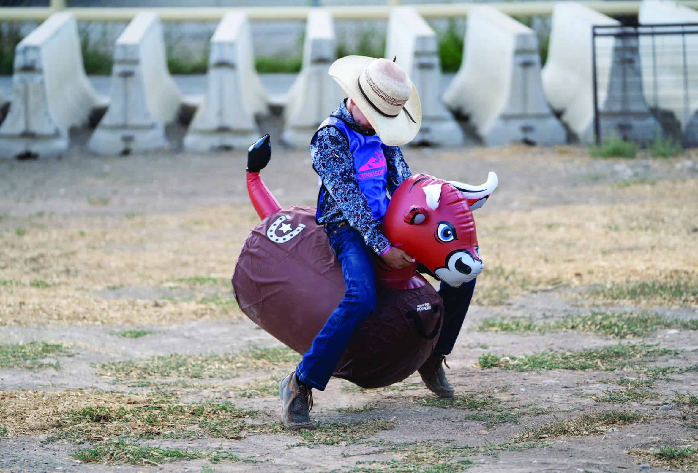 A young buckeroo rides a fierce beast of a bouncing bull toy.