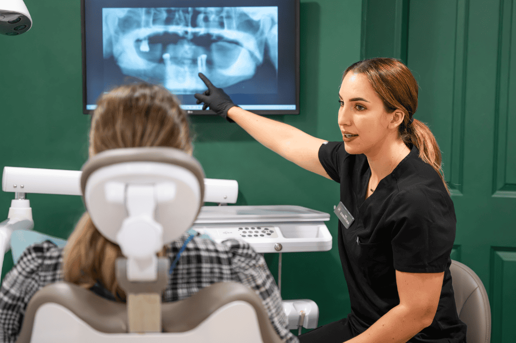 Dentist explaining dental X-ray to patient in a clinic setting.