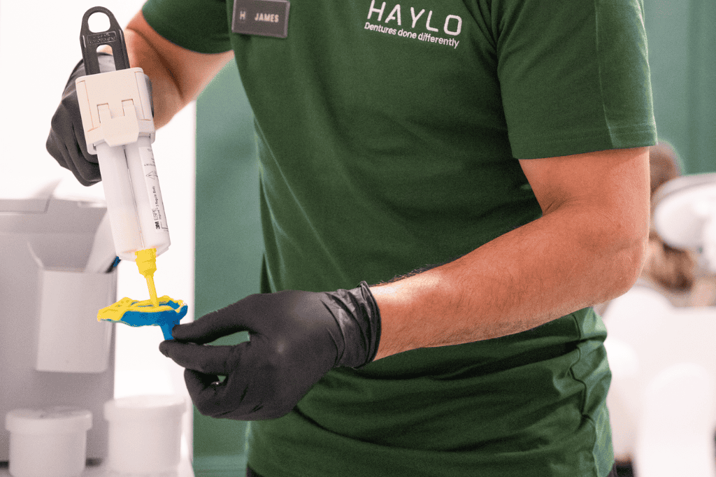Dental professional preparing dental material with a syringe in a clinic.