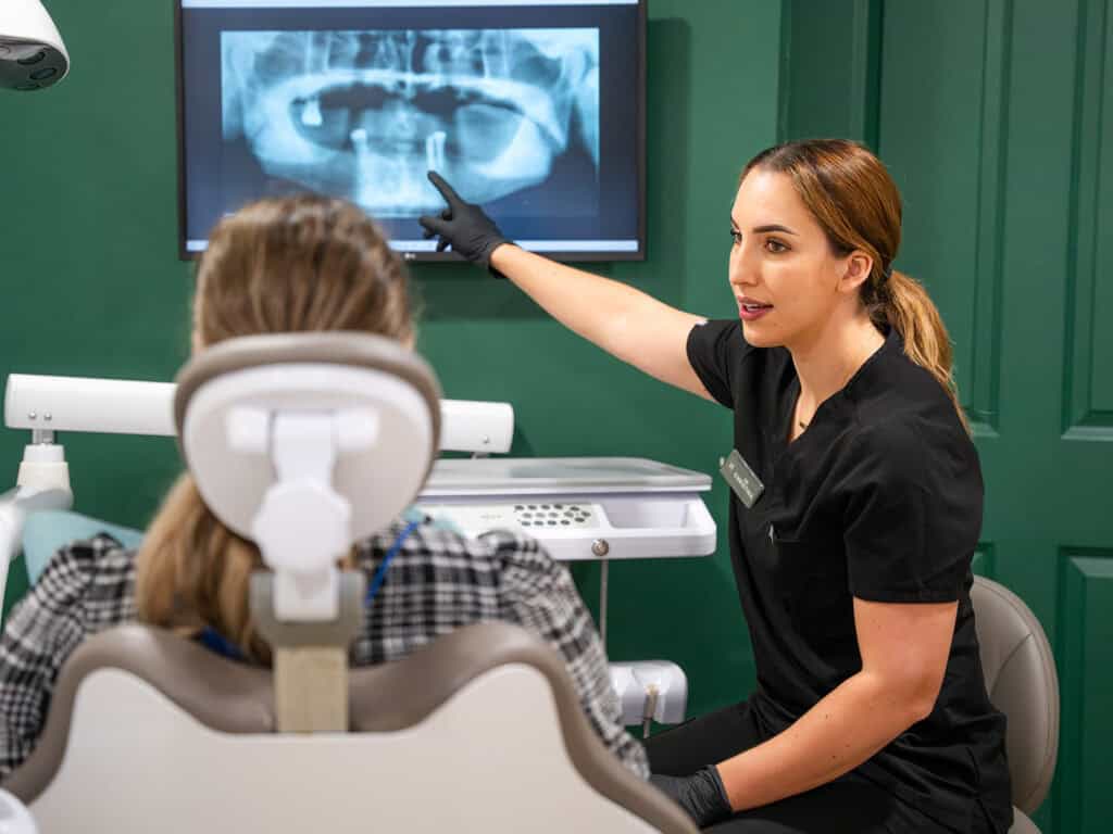 Dentist explaining dental X-ray to patient in clinic.