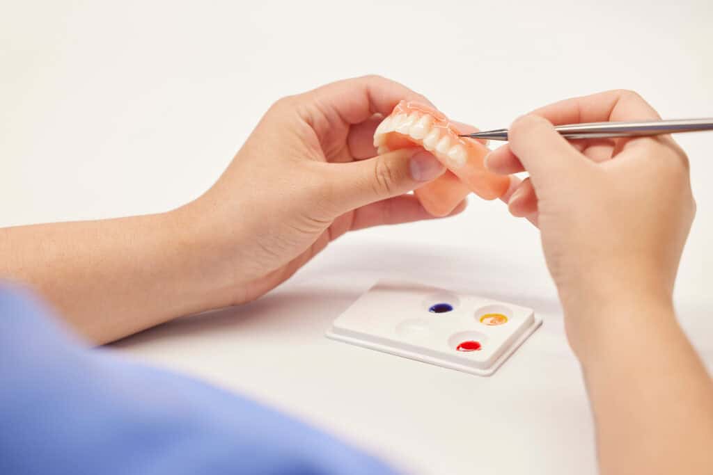 Dentist preparing a dental prosthetic with a model and tools at Haylo Dental.