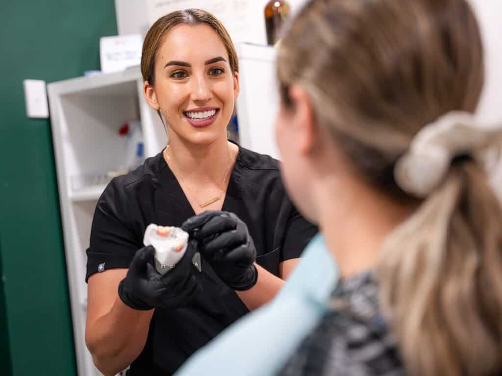 Dental professional showing dental model to patient in clinic.