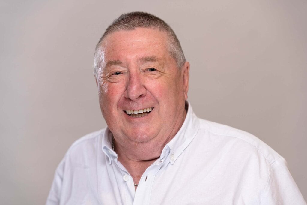 Smiling older man in white shirt, promoting dental health services.