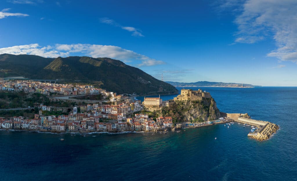 drone view of the seaside town of Scilla in Calabria, Southern Italy with blue sea and green hills in background