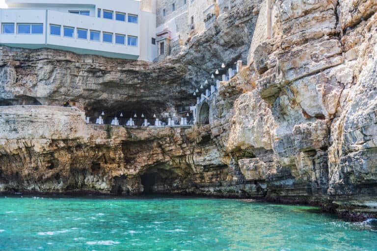view from sea level looking up at the Grotta Pallazesse cave restaurant with the tables on the edge of the cliff.