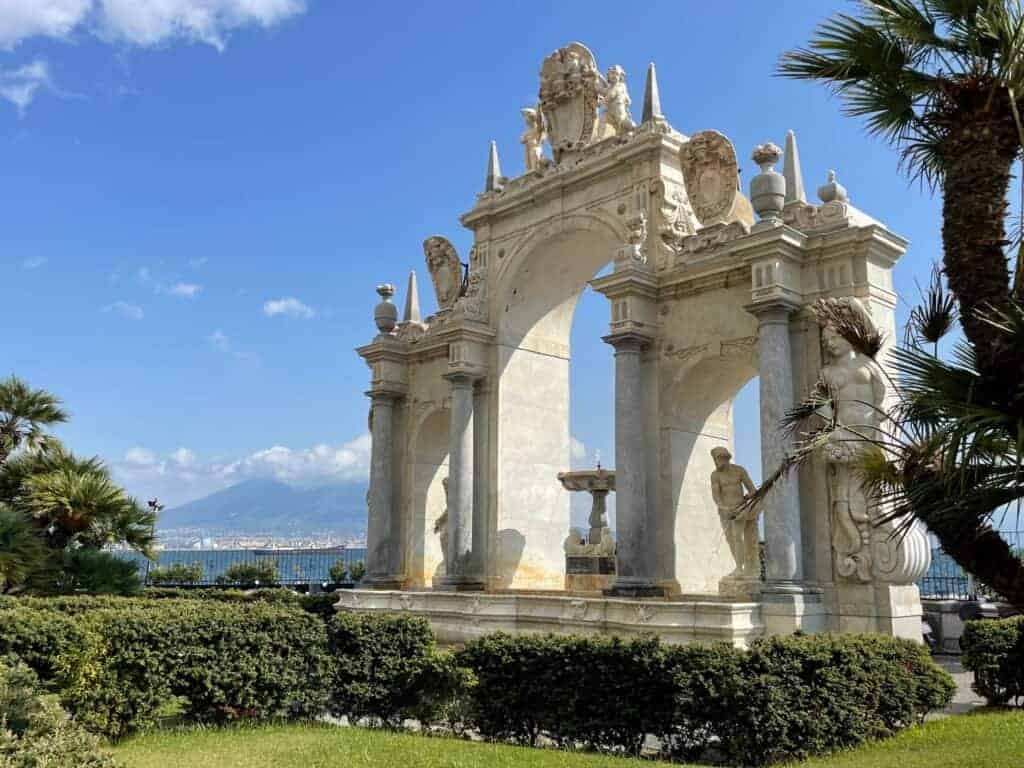 'Fontana del Gigante' monument on Naples Waterfront on a sunny day with blue skies and mount Vesuvius in the far background