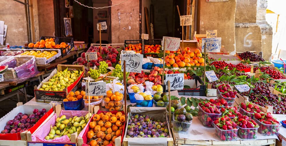 colourful image of varied fresh fruit  including strawberries, pears, plums, cherries, grapes and nectarines on a market stall in wooden boxes.