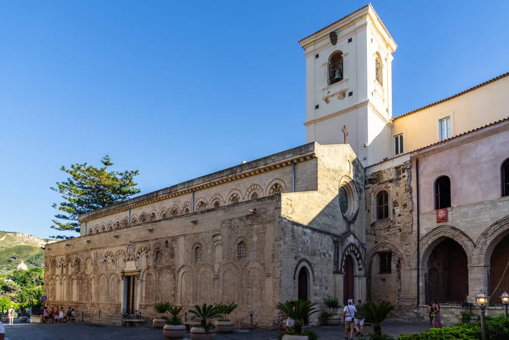 Things to see in Tropea. 12th century cathedral in stone with a bell tower on a sunny day with blue cloudless sky.