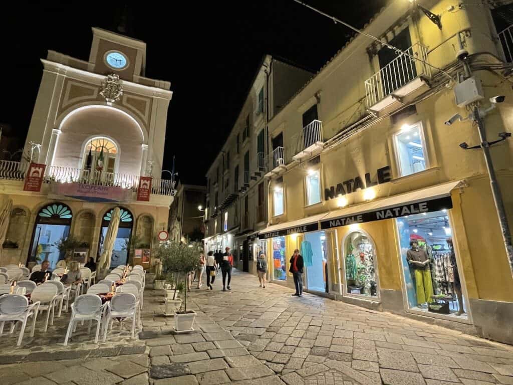 Nighttime street scene with shops, cafe and people