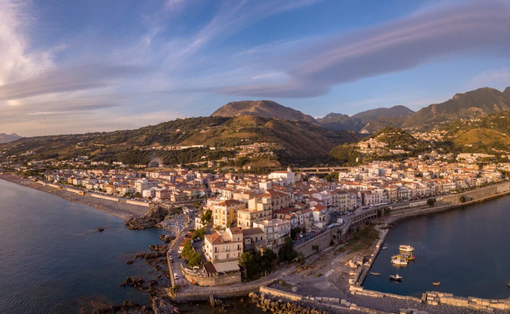 aerial view of the town of Diamante from seaward of a town built on rocky headland and the blue sea either side of the headland.