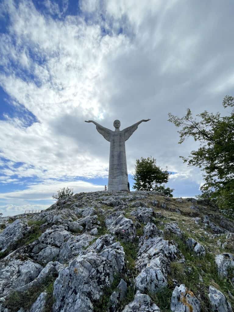 view looking up at the statue of Christ the redeemer sitting on a rocky terrain on a semi cloudy sunny day