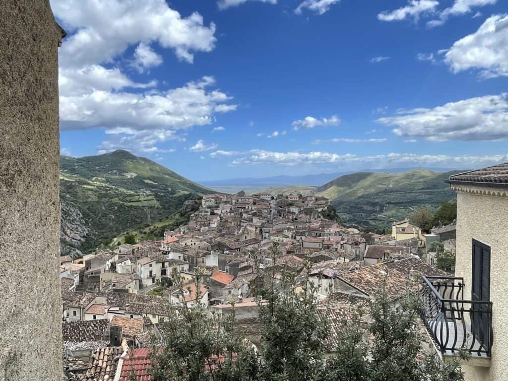 view from a hilltop village looking down through a valley over the old terra cotta roof tops and the distant hills and sea on the far horizon