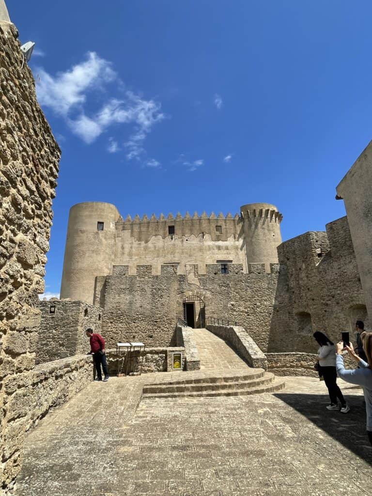 Image of a stone castle with circular towers each side on a sunny day
