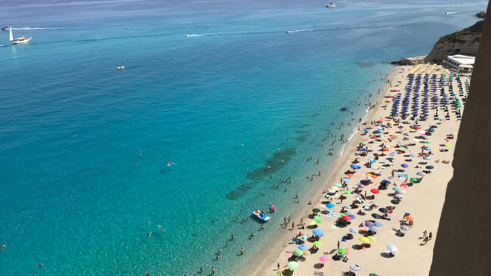 Beautiful Tropea beach with vibrant umbrellas and clear blue water.