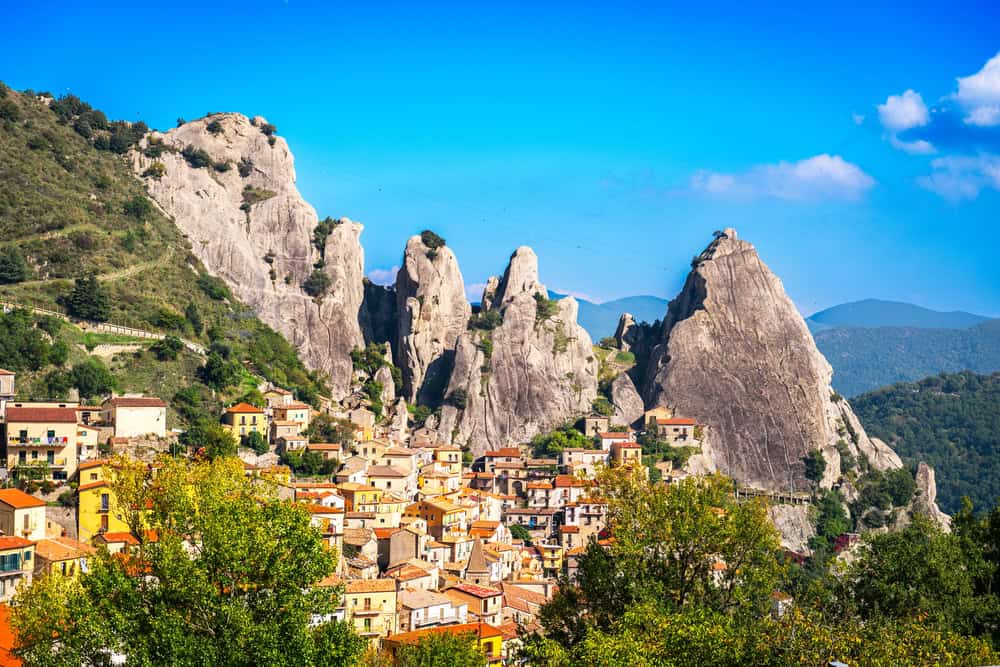 hitoric mountain village of Castelmezzano, with jagged rocky peaks behind the village on a blue sky day
