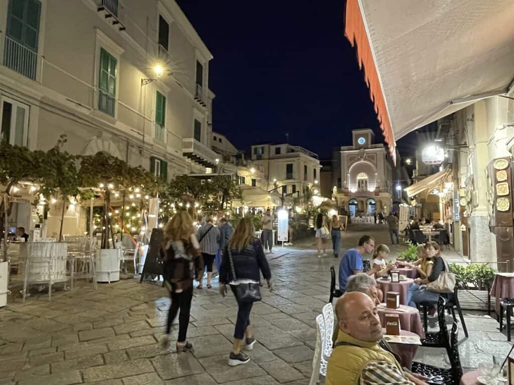 Vibrant night scene in Tropea with outdoor dining and historic architecture.