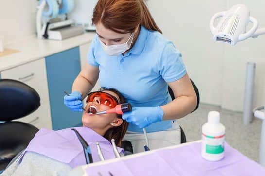 Modern dental clinic with a dentist performing a cleaning procedure on a patient.