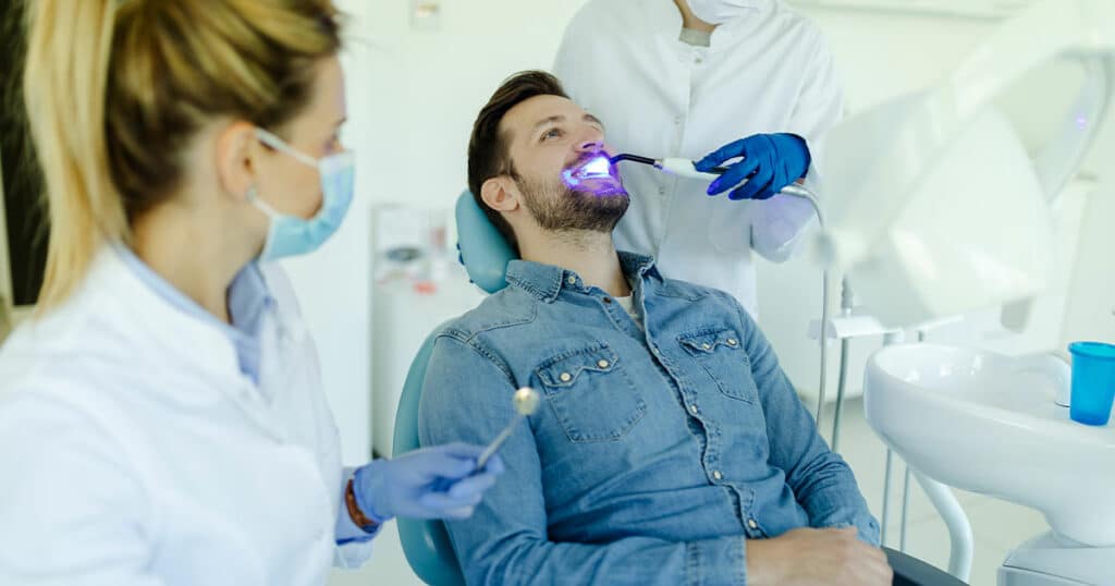 Brightly lit dental clinic with patient receiving LED teeth whitening treatment at Heritage Dental Edmonton.