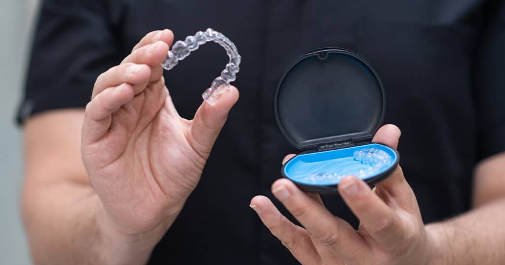 Clear Invisalign aligners in hand, ready for teeth straightening at Heritage Dental Edmonton.