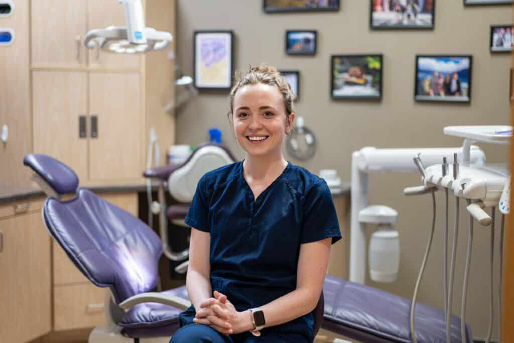 Friendly female dental professional sitting in a modern dental clinic, ready to provide dental care services.