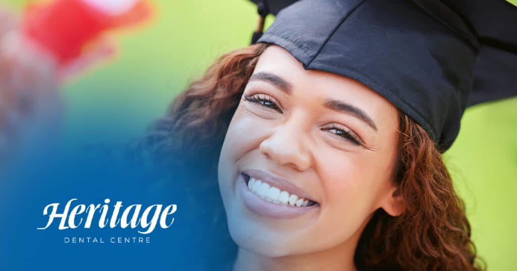 Smiling woman in graduation cap, happy dental patient, bright smile, Heritage Dental Centre, confidence, joyful celebration of dental care success.