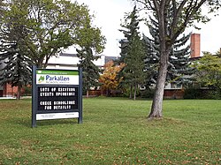 Parkallen outdoor sign in a green park area with trees, promoting dental services and community health in Edmonton.