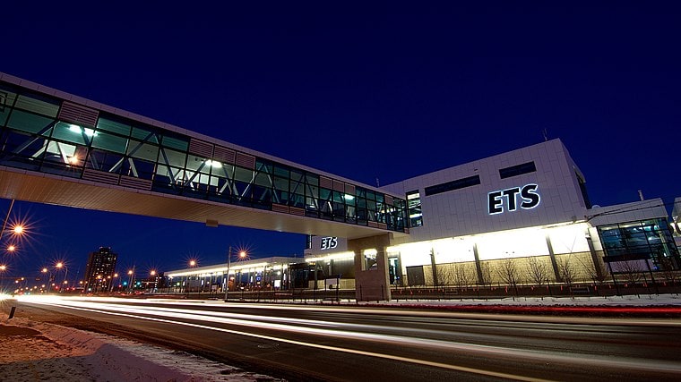 ETS building at night in Edmonton, modern architecture with illuminated signage and a skybridge connecting to another structure. Well-lit exterior highlighting an urban environment.