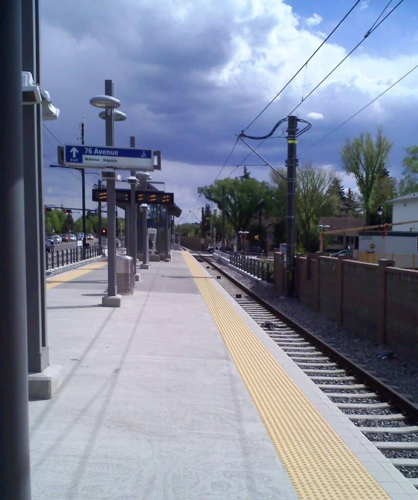 Modern train station platform in Edmonton with clear signage, safety tactile paving, and accessibility features, providing convenient transportation options for commuters near Heritage Dental Centre.