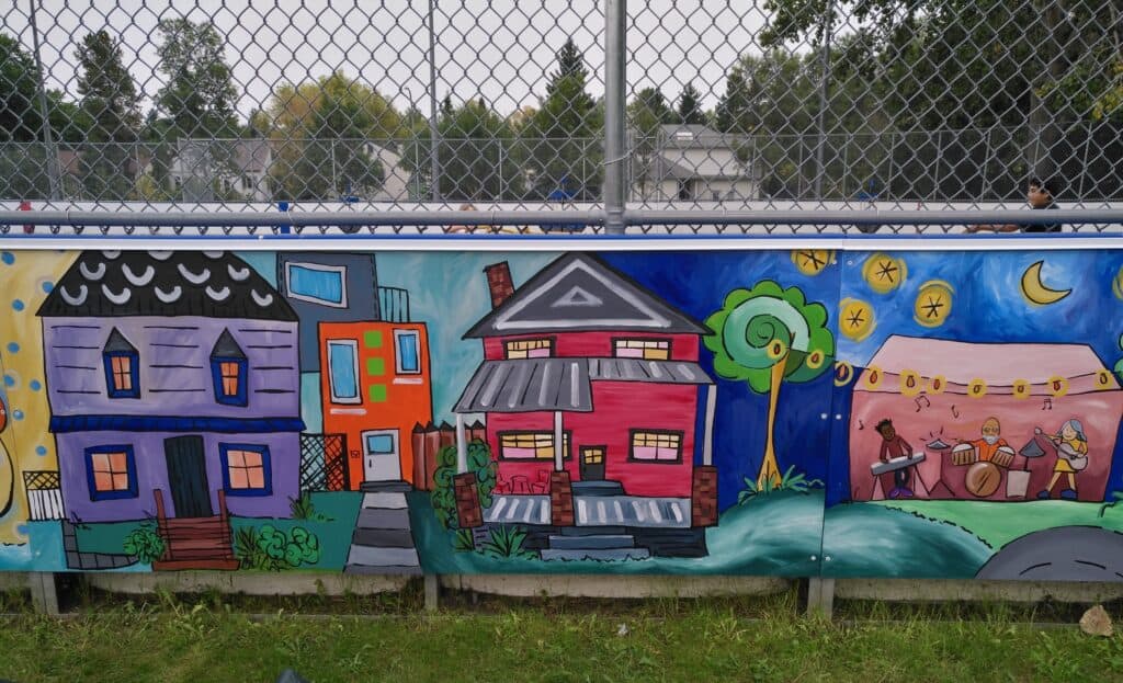 Colorful mural on outdoor fence with houses, trees, and night sky, promoting community art and local culture. Perfect for enhancing the neighborhood's visual appeal and engaging residents of Edmonton.
