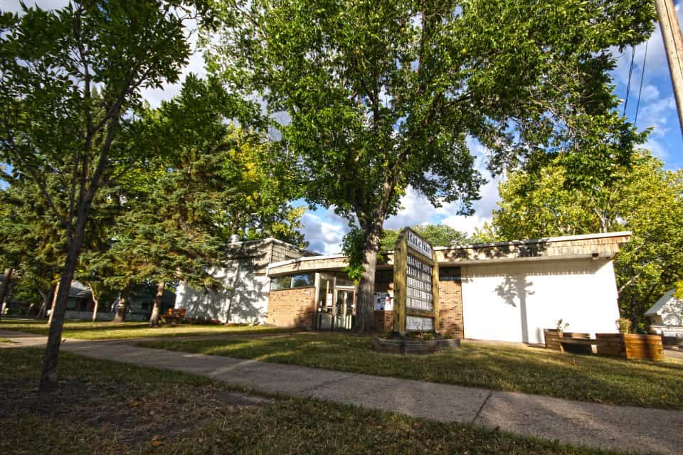 Ritchie Hall exterior building in Edmonton surrounded by lush green trees and a clear blue sky.