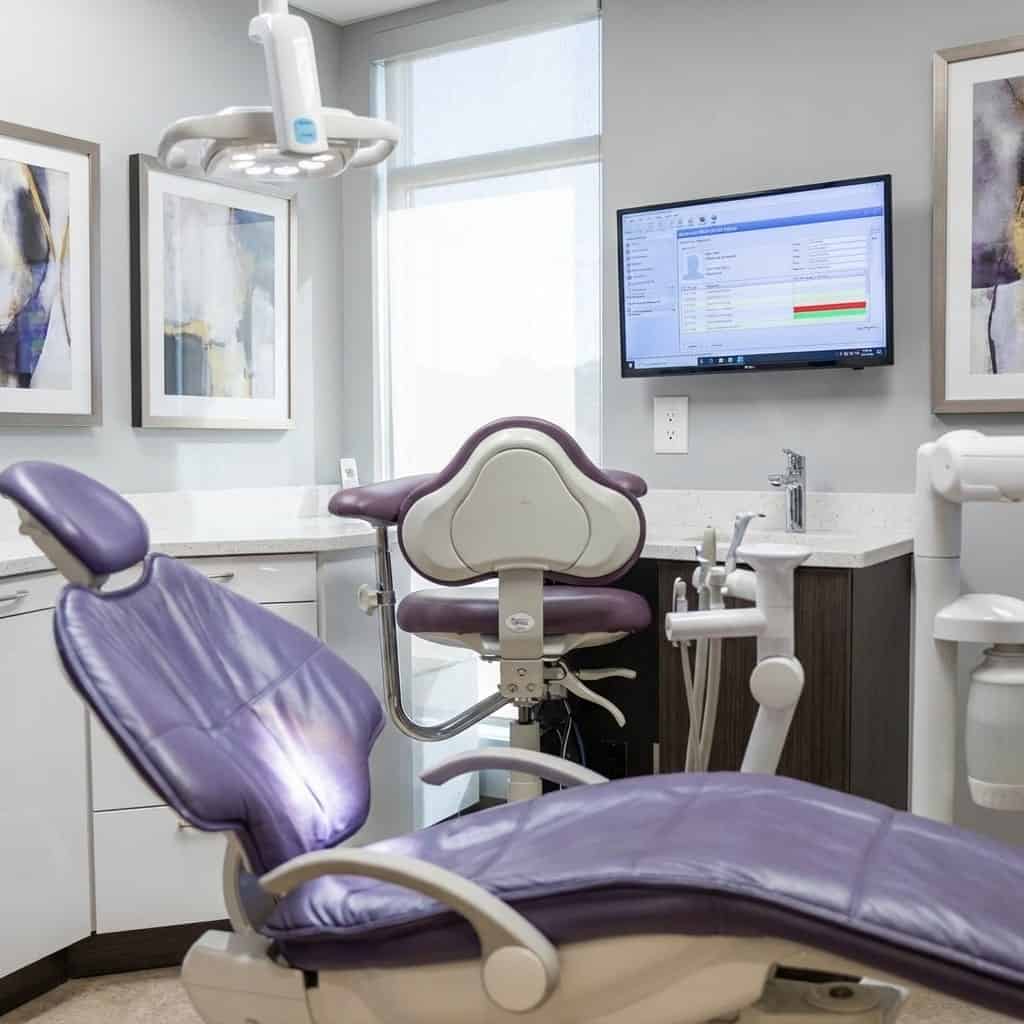 Modern dental clinic with exam chair, dental light, computer monitor, and artwork. Bright, clean, and welcoming environment designed for patient comfort and advanced dental care.