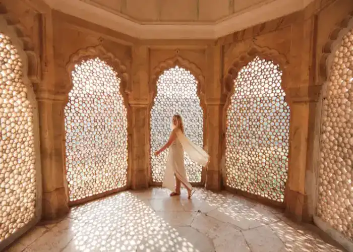 Elegant woman in traditional attire inside historic Rajasthan pavilion.