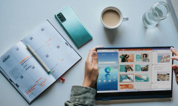 person using Windows 11 computer beside white ceramic mug on white table