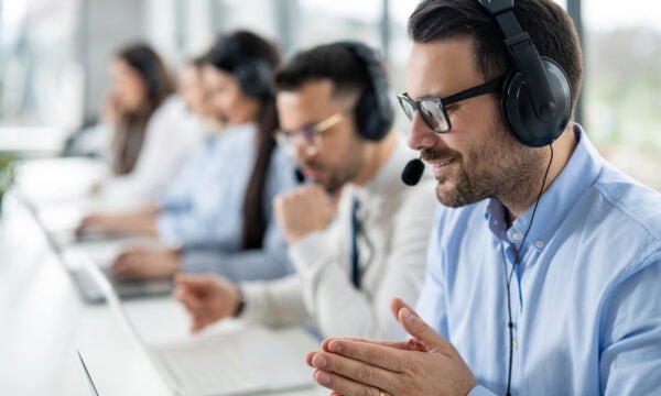 Close up portrait of handsome man with headset successfully solving task to his client during online chat in call center
