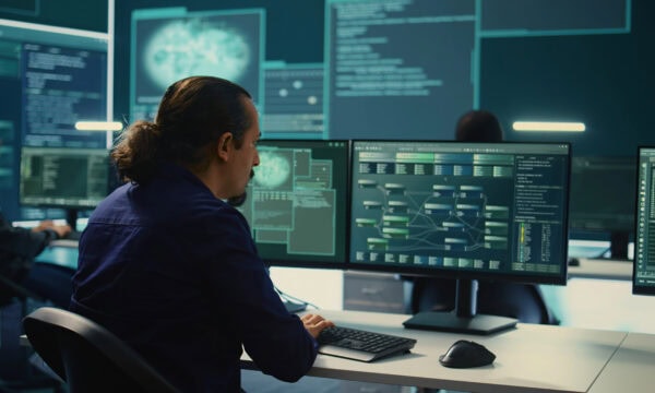 IT expert monitoring cyber threats on a computer and big screen, high tech agency office.