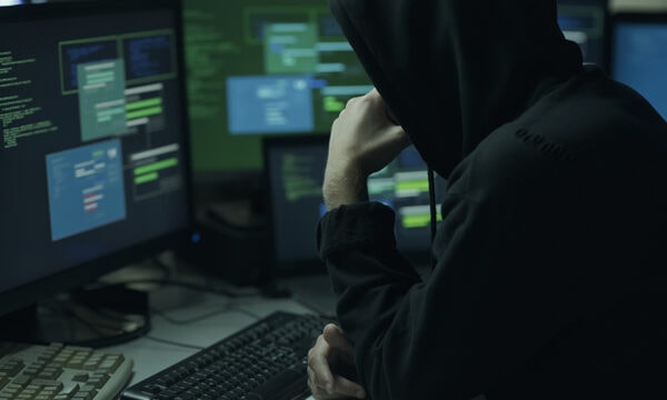 Hacker with hoodie working with a computer