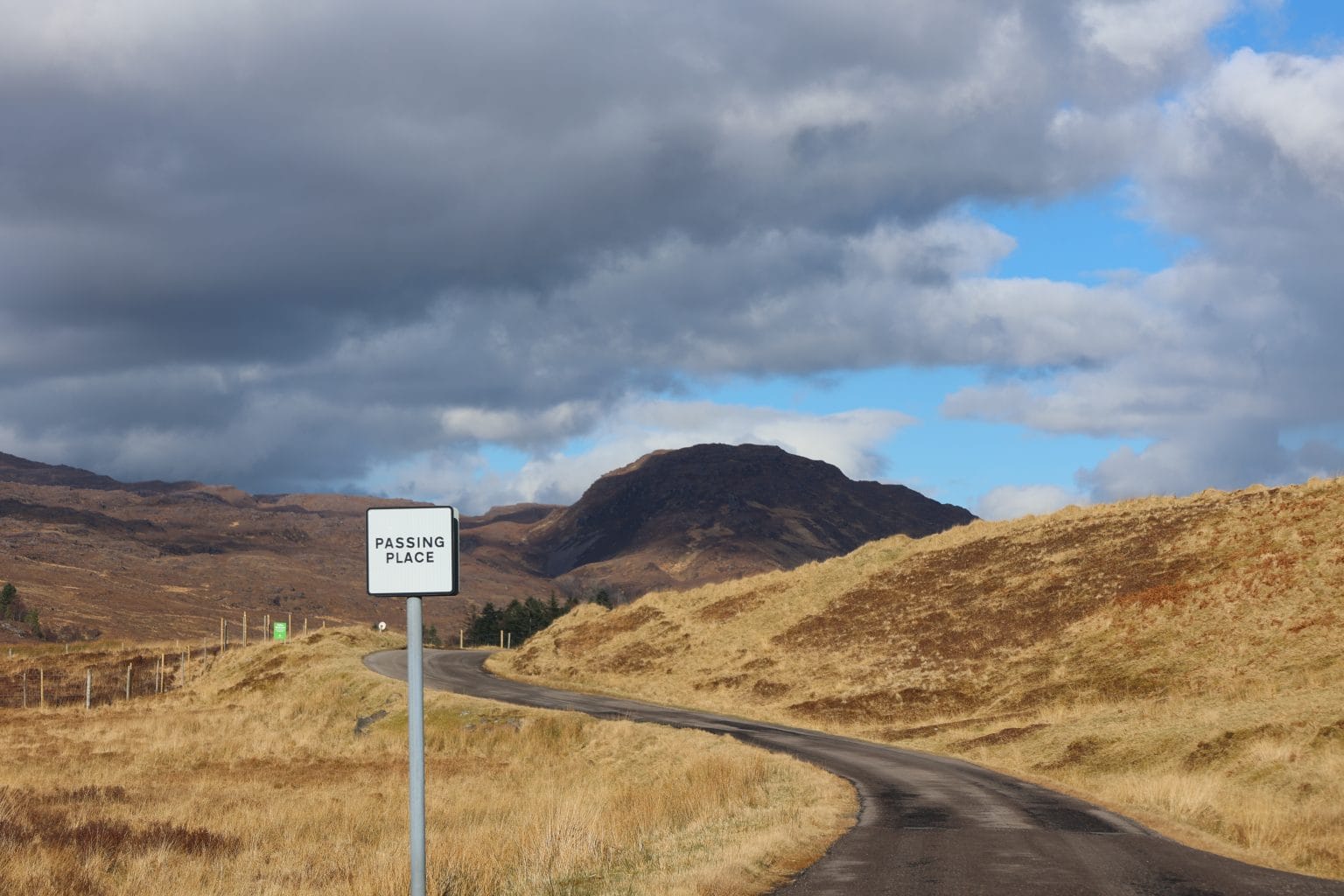 Scottish Highland winding single track road with passing place sign