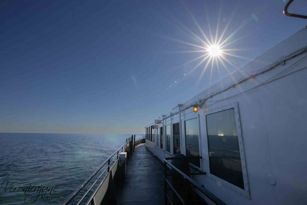 A sunburst shows in the sky above the SS Badger while only showing water in the background